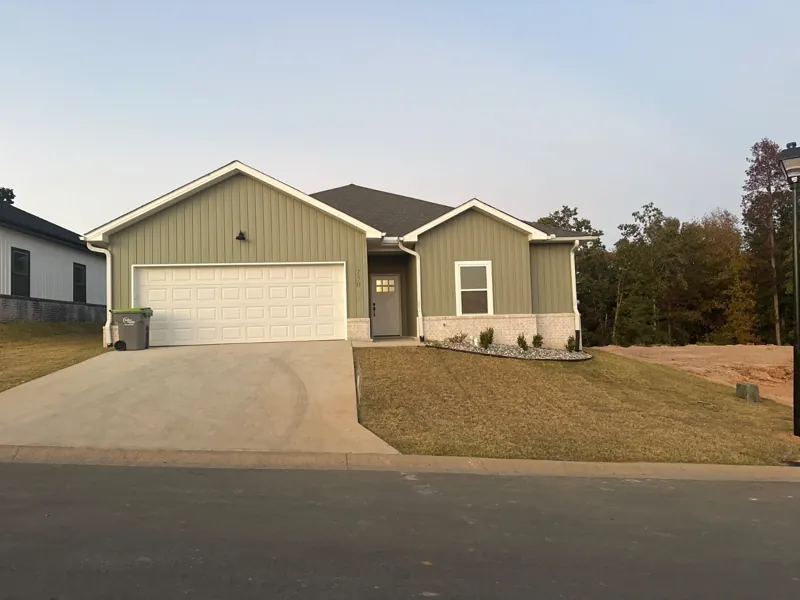 A green four-bedroom home with fall trees behind it